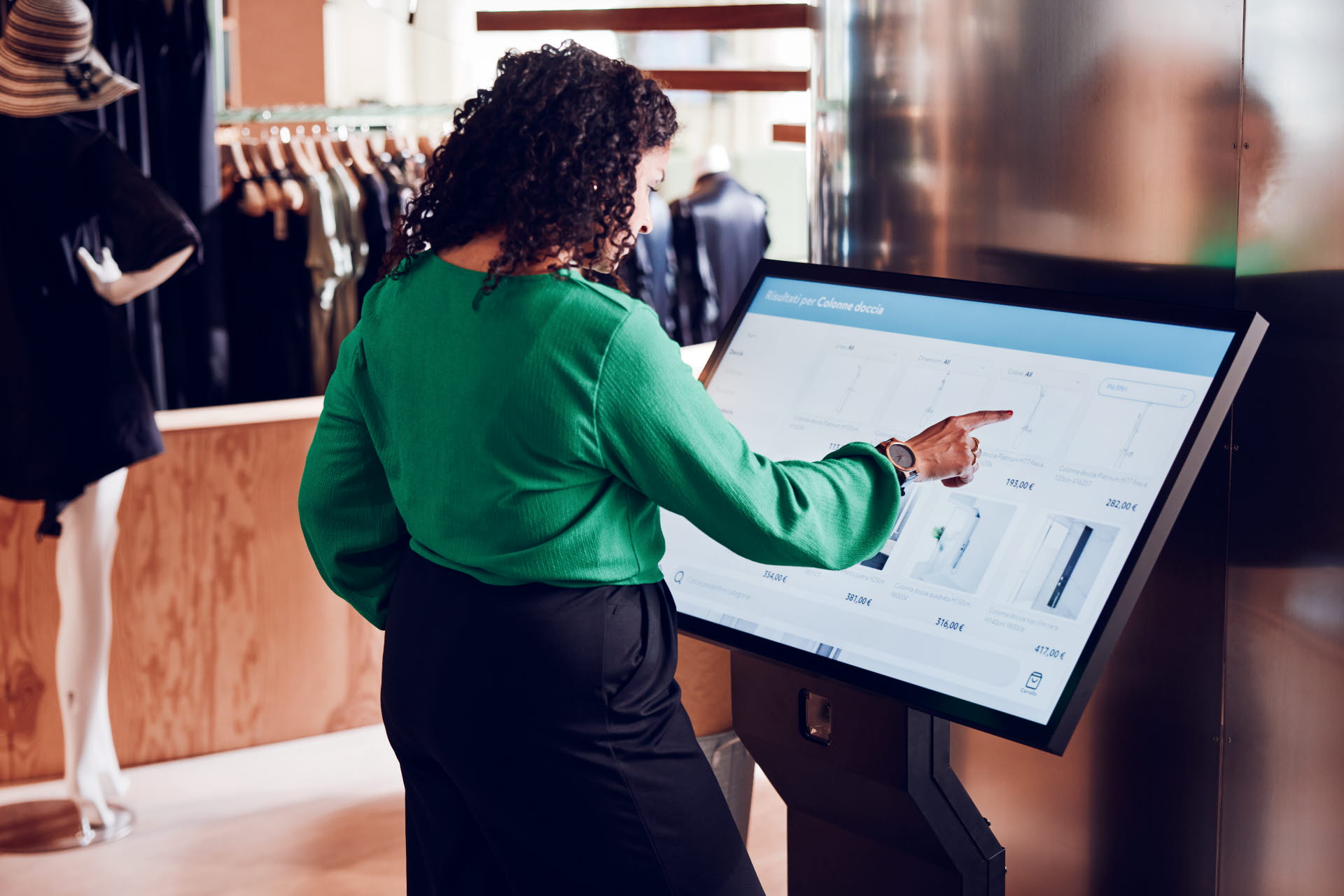 Woman using ITAB Self Service Solution in a fashion store to browse products, check inventory and current offers.